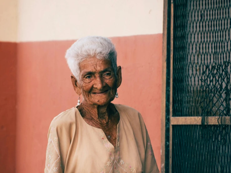 an old lady stands in front of a gate