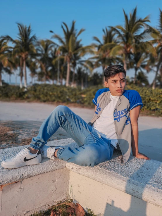 a guy sitting on a ledge with his hands on his knees