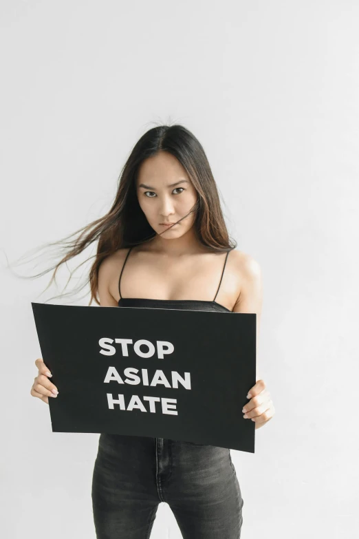woman holding up a sign saying stop asian hate