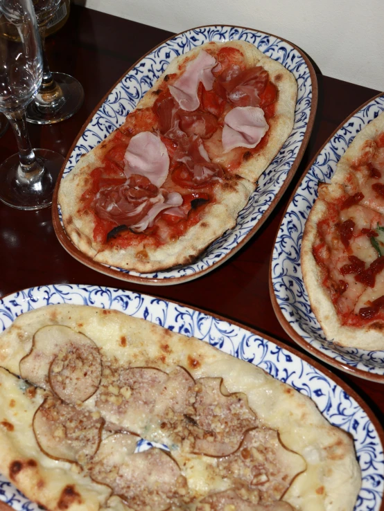 three pizzas are served on plates at a table