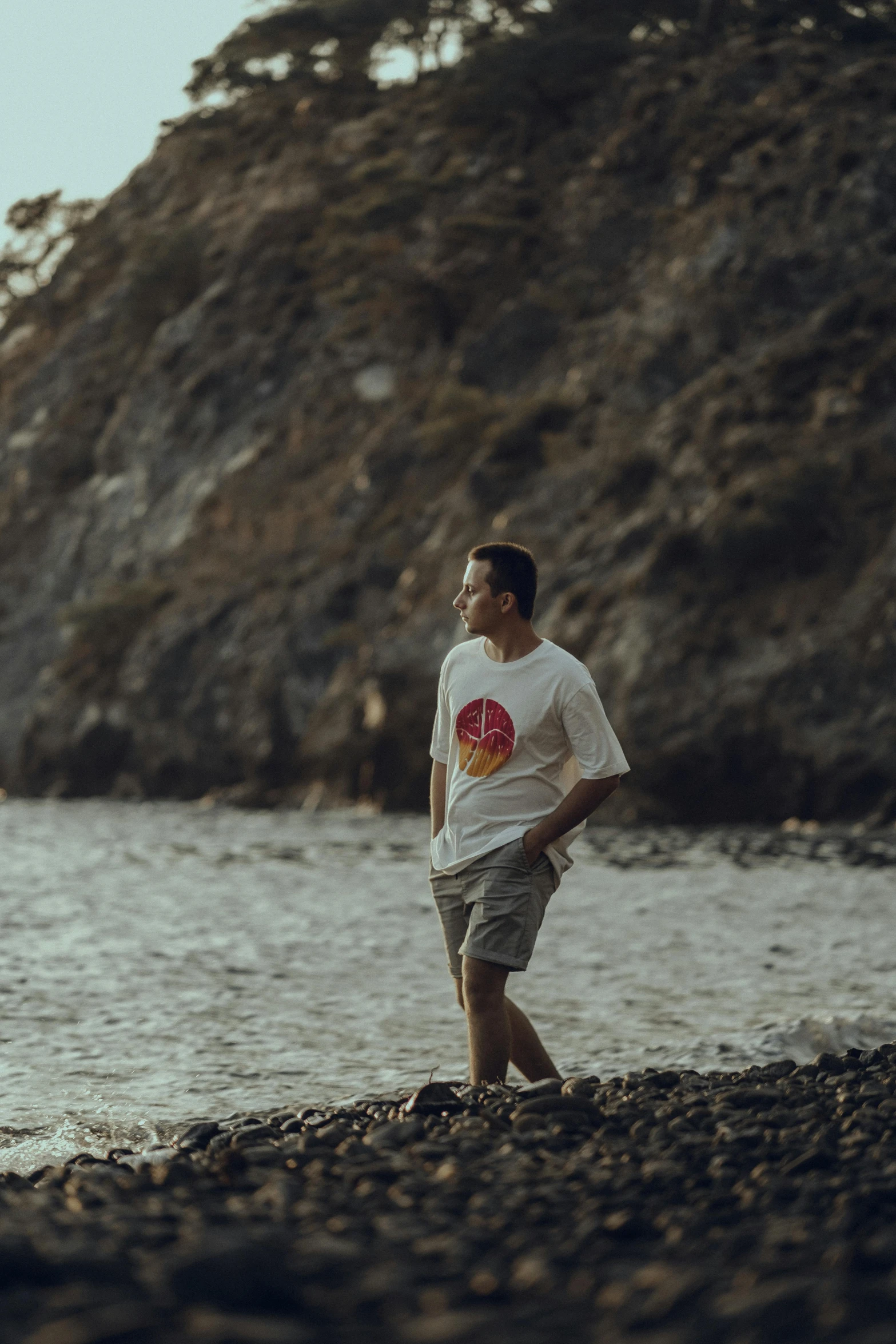 a man in white shirt standing on top of a rocky beach