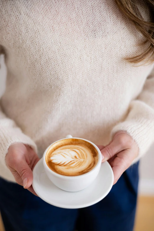 a woman holding a cup with a latte in her hands