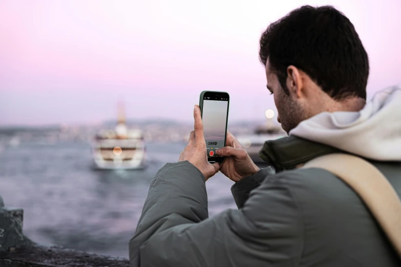 man in the rain holding a smart phone looking at the water