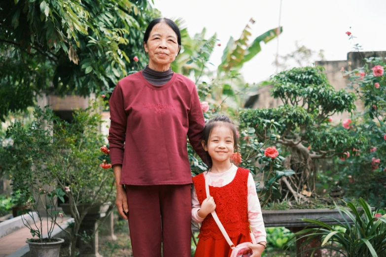 two people wearing dress clothing in front of trees and flowers