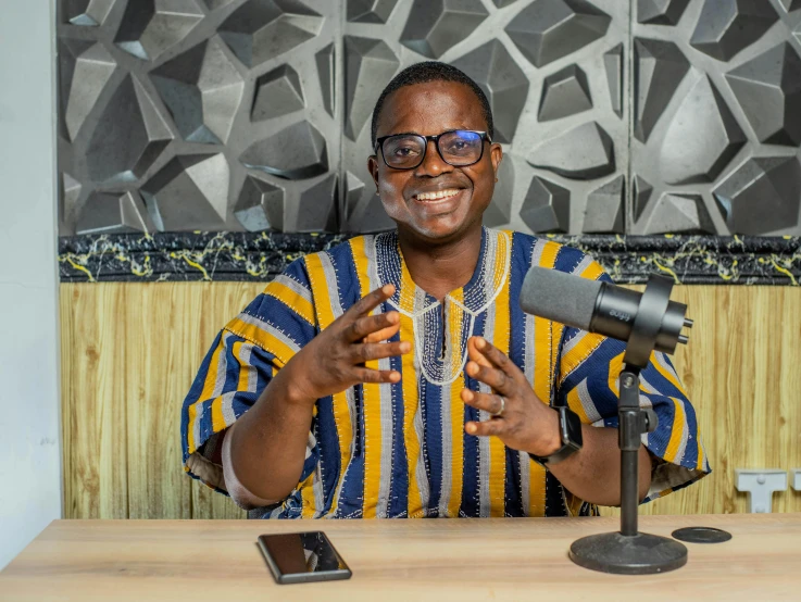 a man stands behind two microphones and smiles