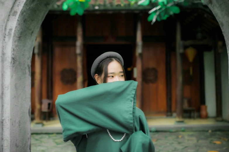 a woman in a green robe covering her face