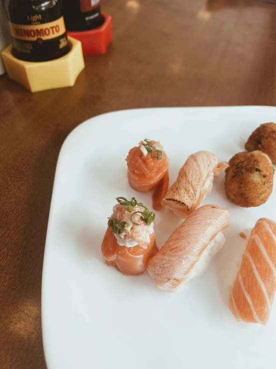 a white plate of sushi, shrimp and rolls