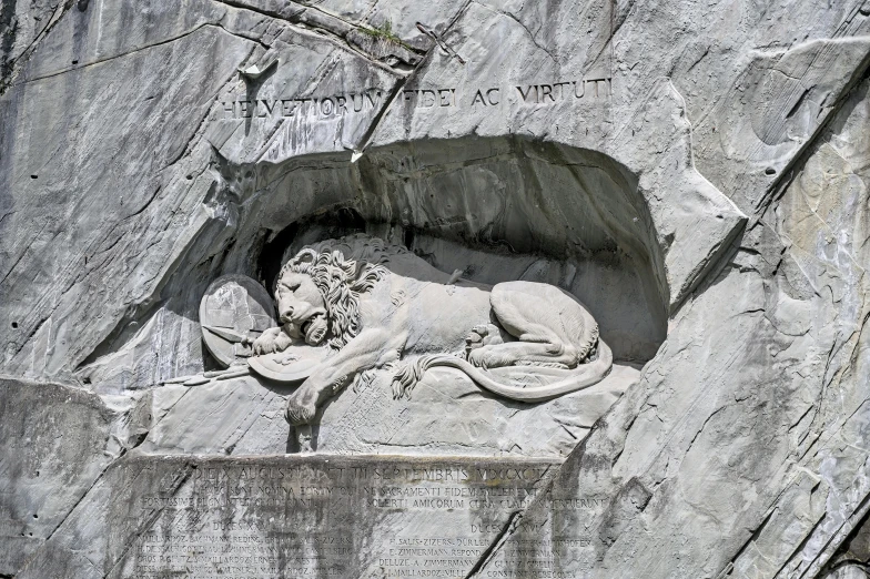 a statue of a lion is placed on the side of a rock