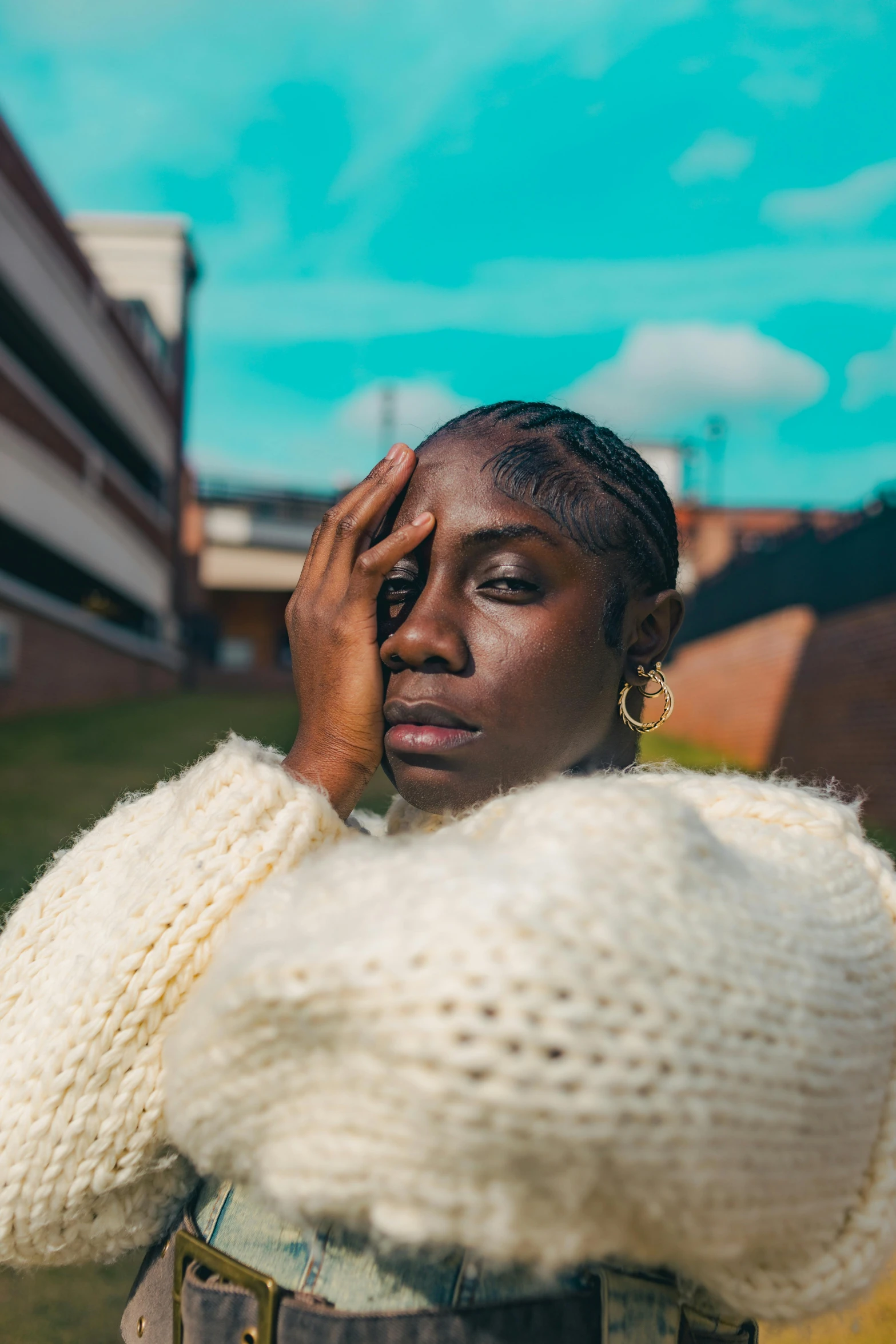 a woman in white sweater standing with her hand on her face