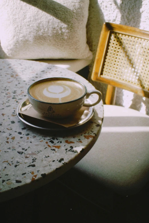 a coffee cup on the table with a yellow chair behind it