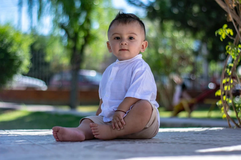 the young child sits on the ground, looking at the camera