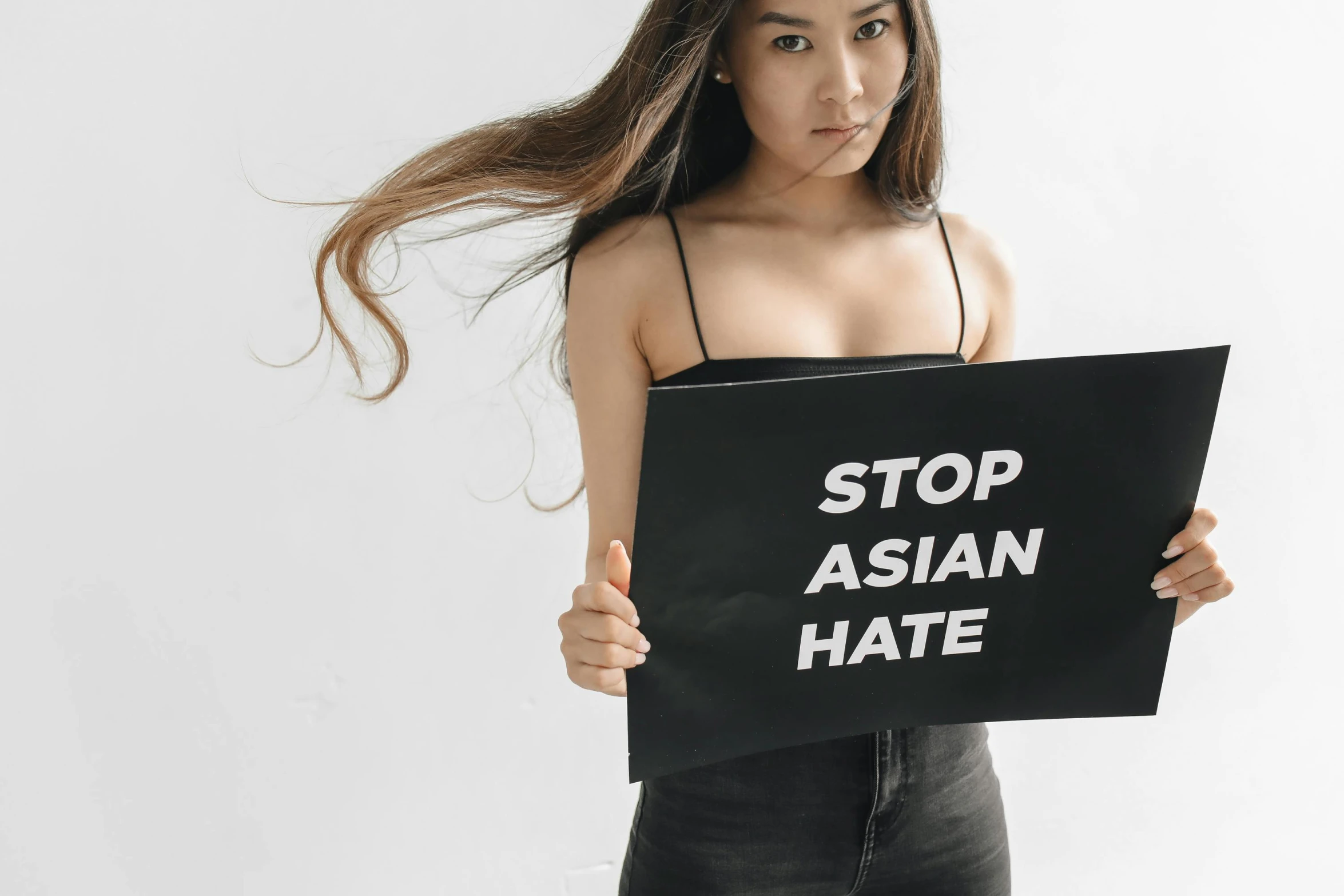 a woman is holding up a stop asian hate sign