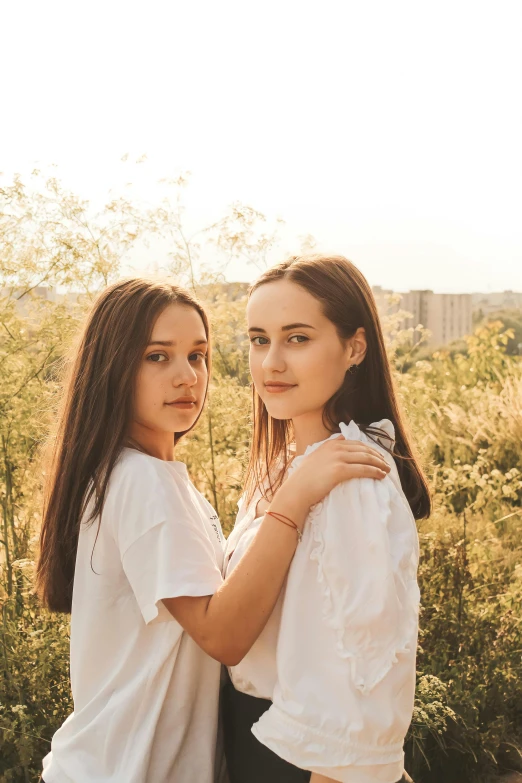 two women in white tops looking out over trees