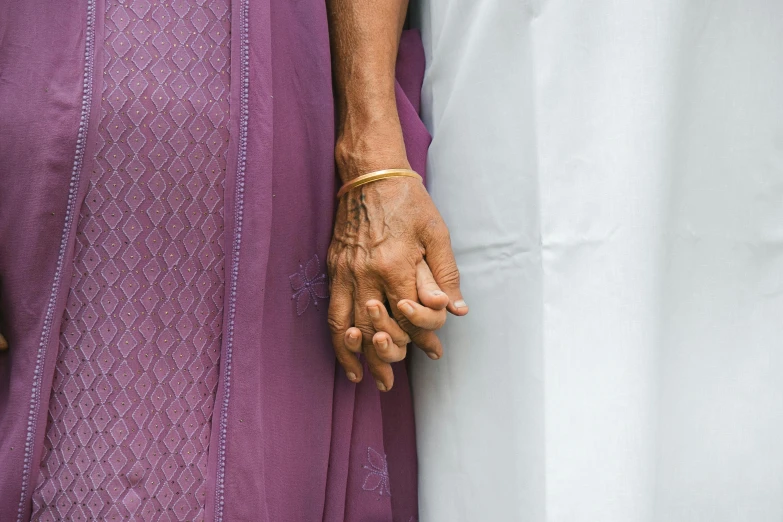 an elderly person holding the hand of a woman