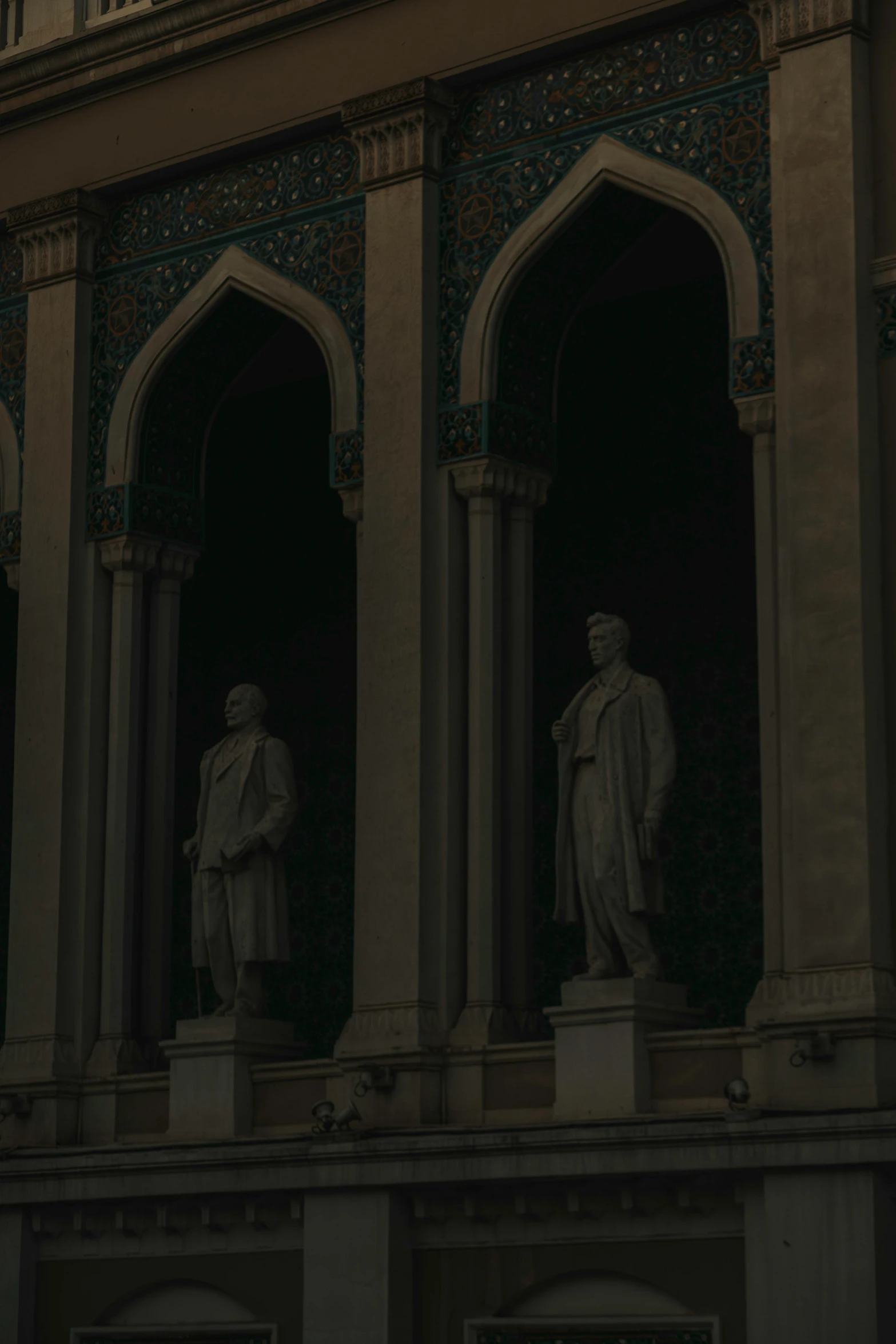 two statues of men stand on a balcony