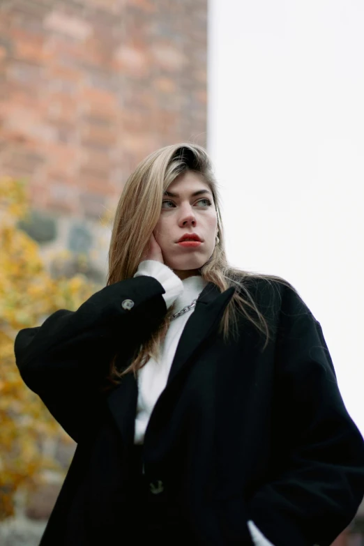 a beautiful young woman wearing a black coat while posing