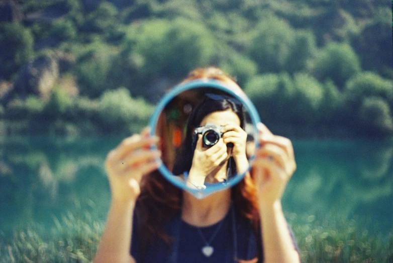 a person with long hair is looking through the lens of a mirror