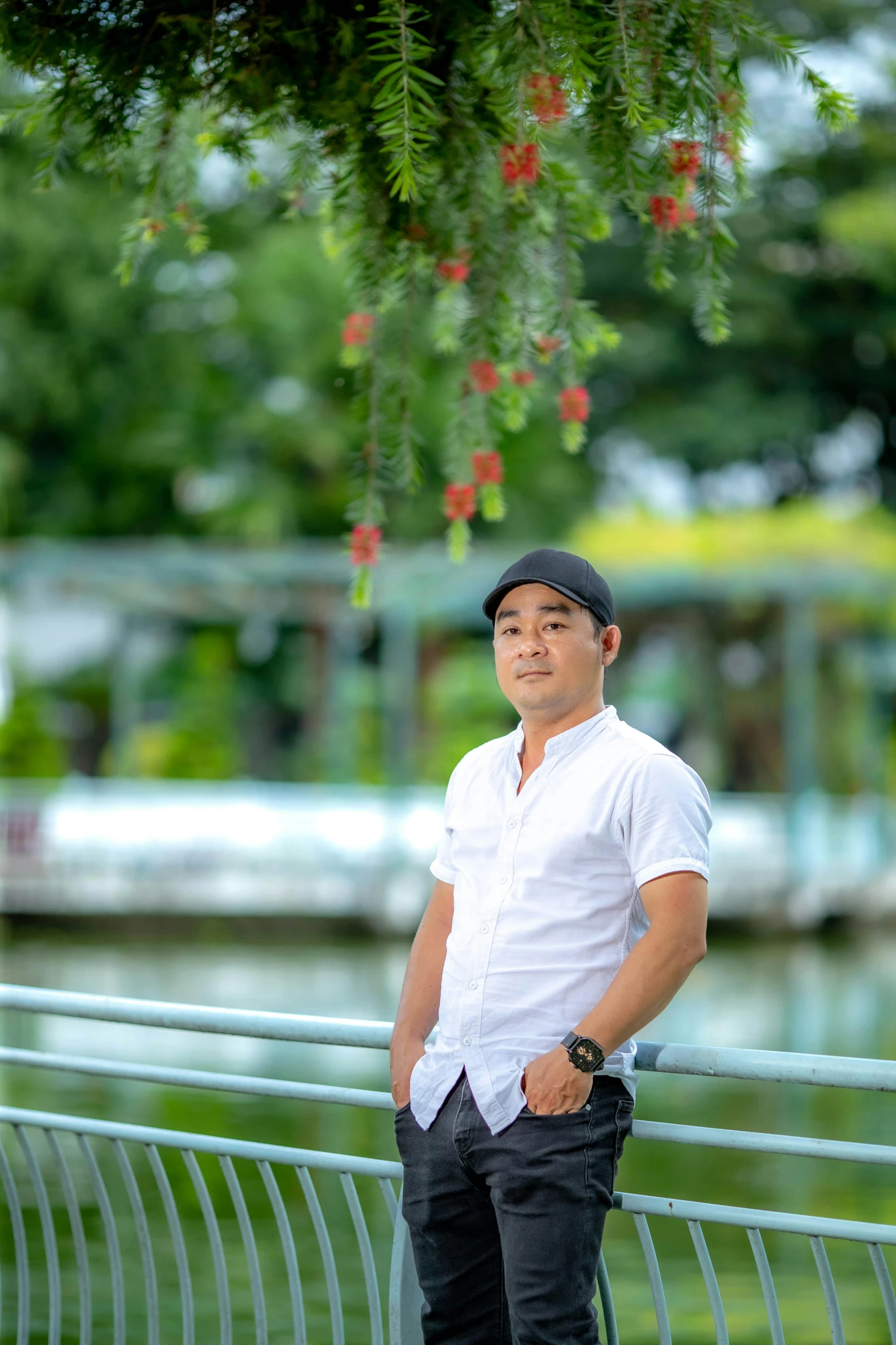 the man in white shirt is posing under a tree