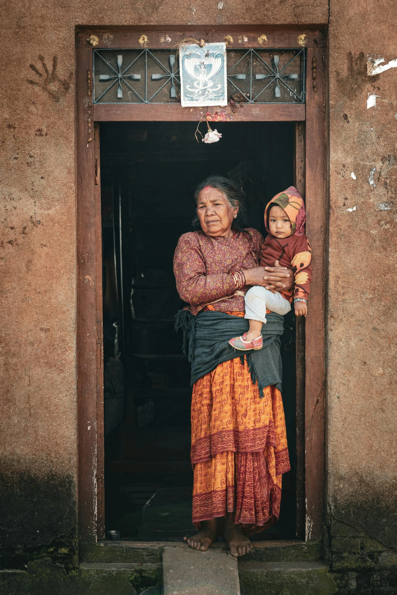 an old lady standing outside the front door holding a child