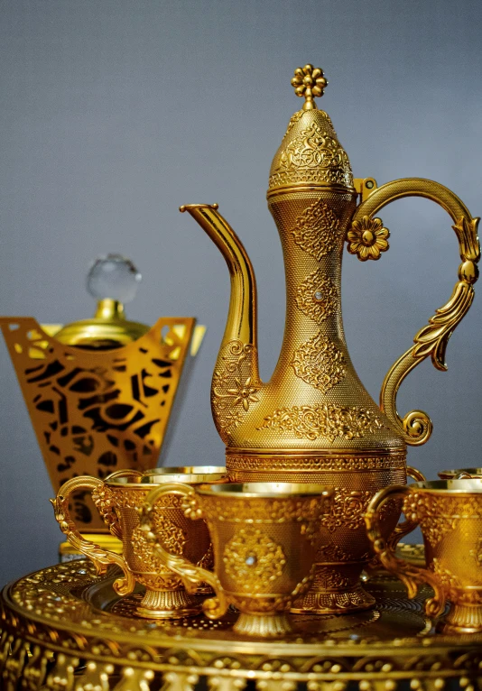 an ornate gold tea set on a silver stand