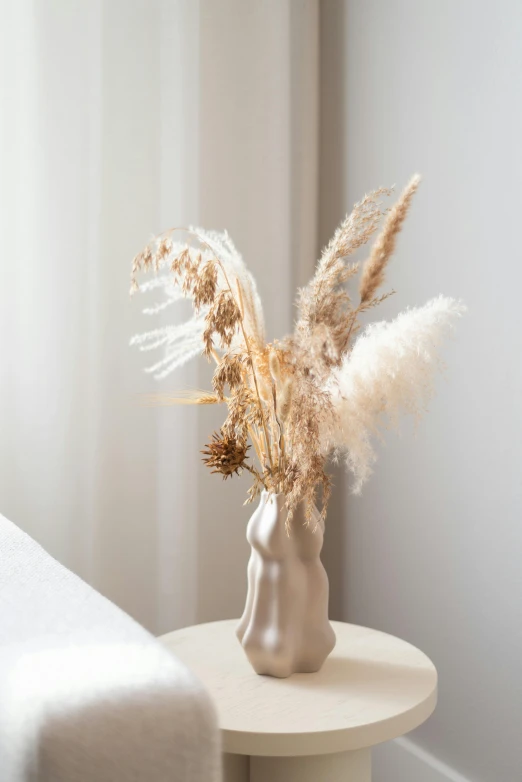 a vase with dry plants on a small table