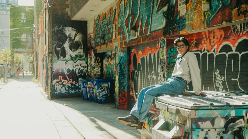 a man sitting on the side of a road covered in graffiti