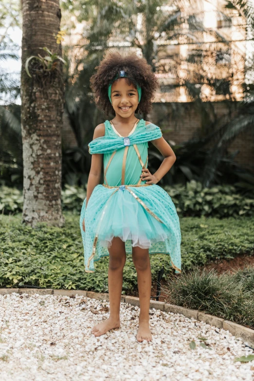 a little girl is dressed up in a turquoise dress