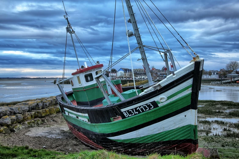 a small green and white boat parked on the shore