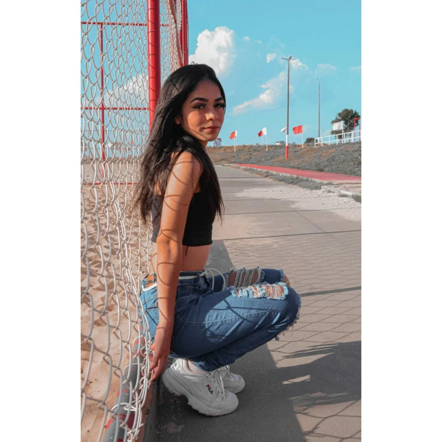 a woman is kneeling down next to a fence