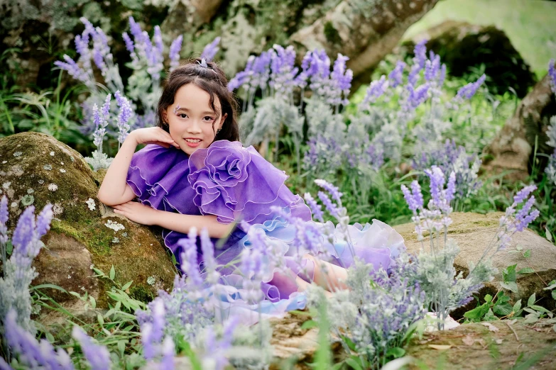 an asian girl sitting on a rock among flowers