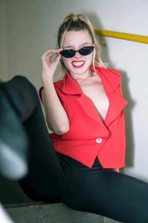 a woman in black pants, red shirt and black sun glasses smiling