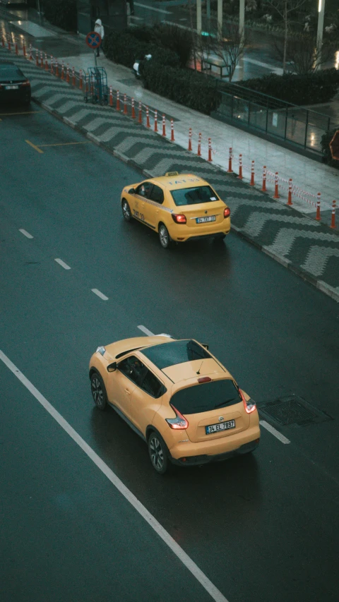 two yellow cars driving in a street with some traffic