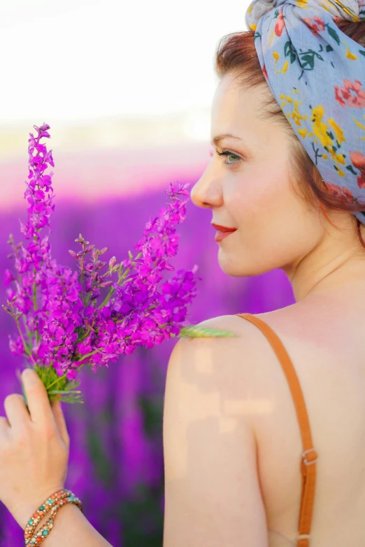 a girl in a field with purple flowers is holding a bouquet of flowers