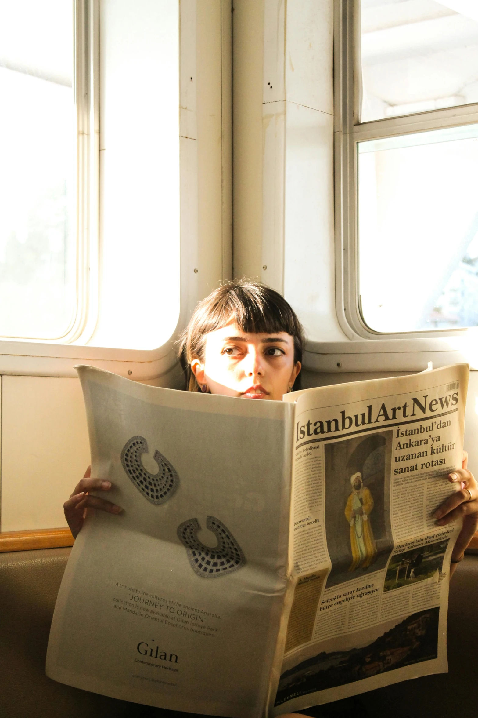 a girl sitting on a bench looking at a newspaper