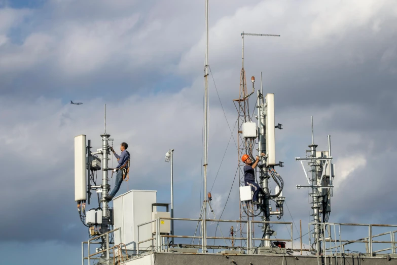 two people working on a antennas atop an aircraft