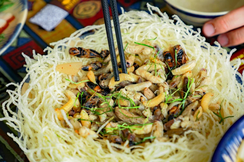 someone is holding chopsticks over the noodles in this meal