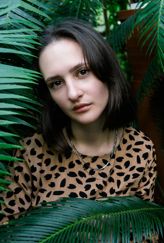 a woman in a leopard dress with plants behind her