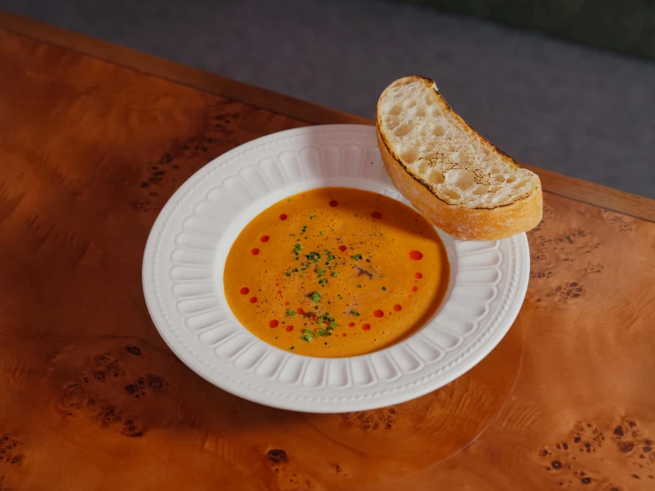 the bowl of soup is next to a slice of bread