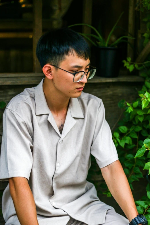 a man sitting down with black glasses and a white shirt on