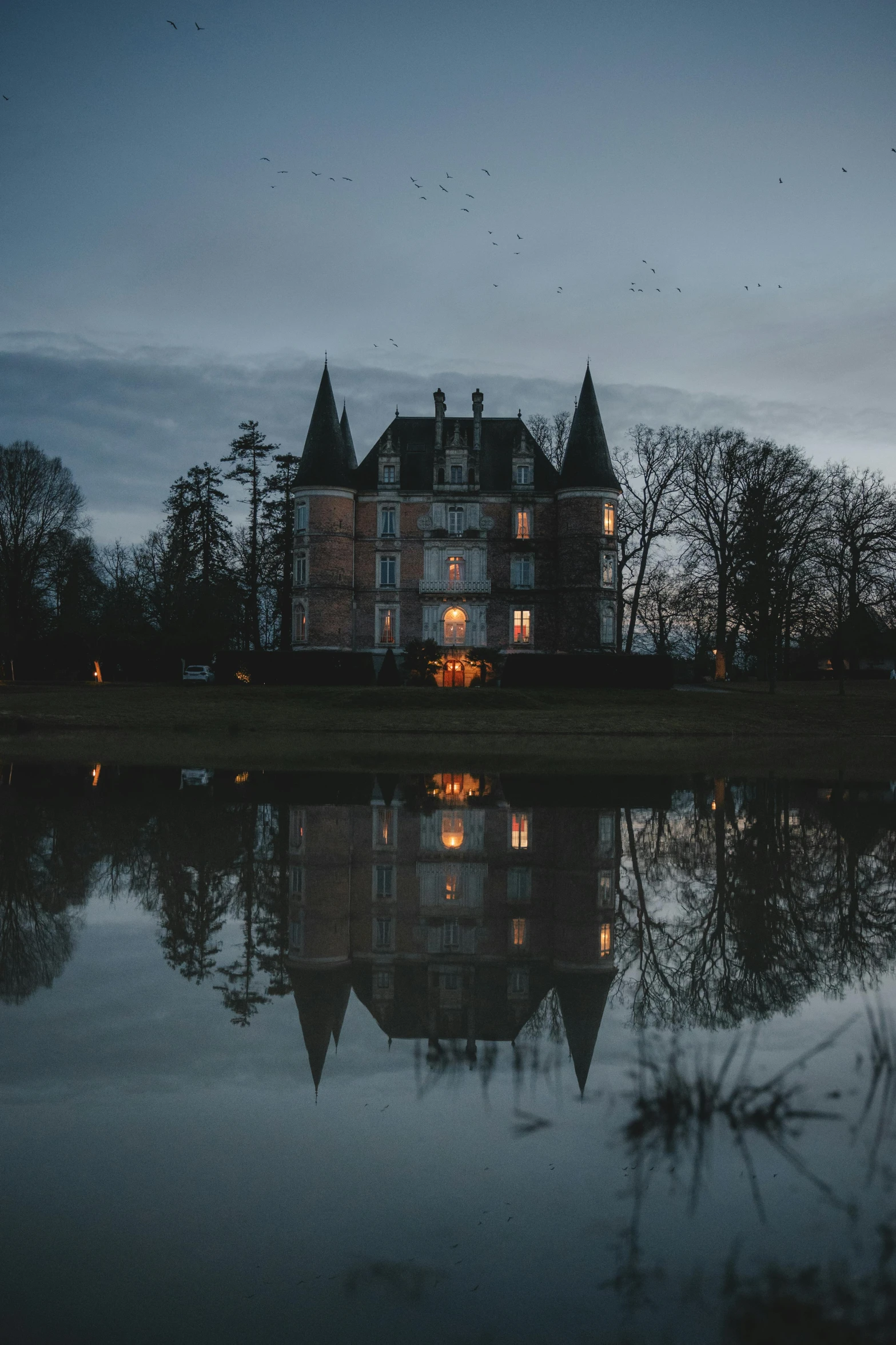 the large building is illuminated by candles over a pond