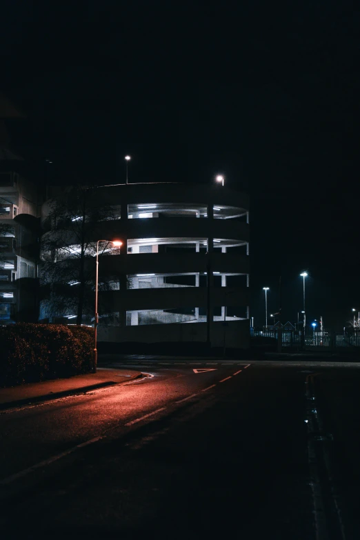 an empty road at night with a building in the background