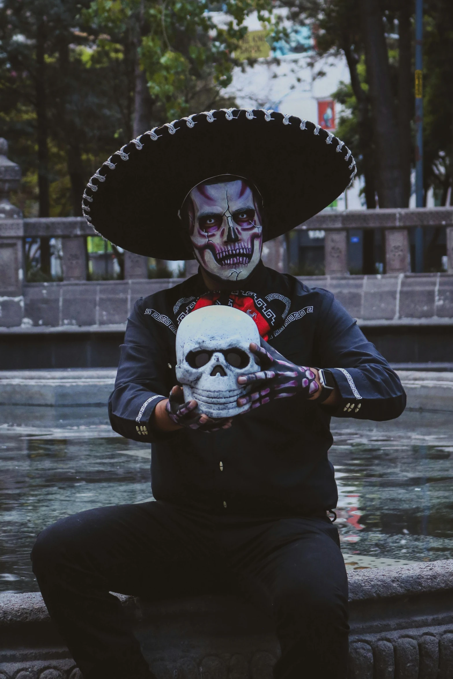 a skeleton wearing sombrero holding up a skull