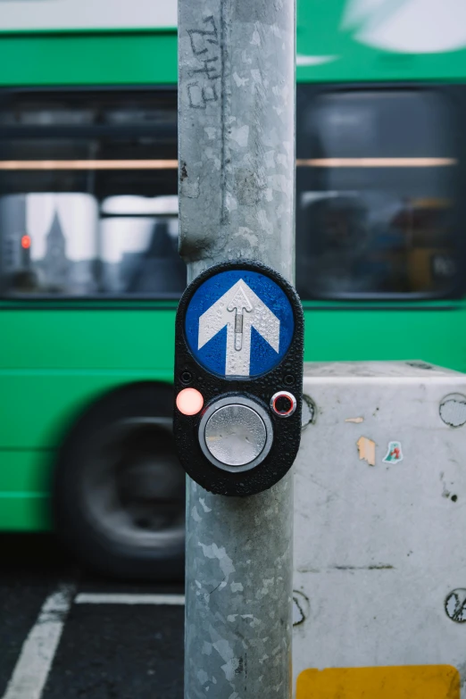 there is a green bus next to a pole