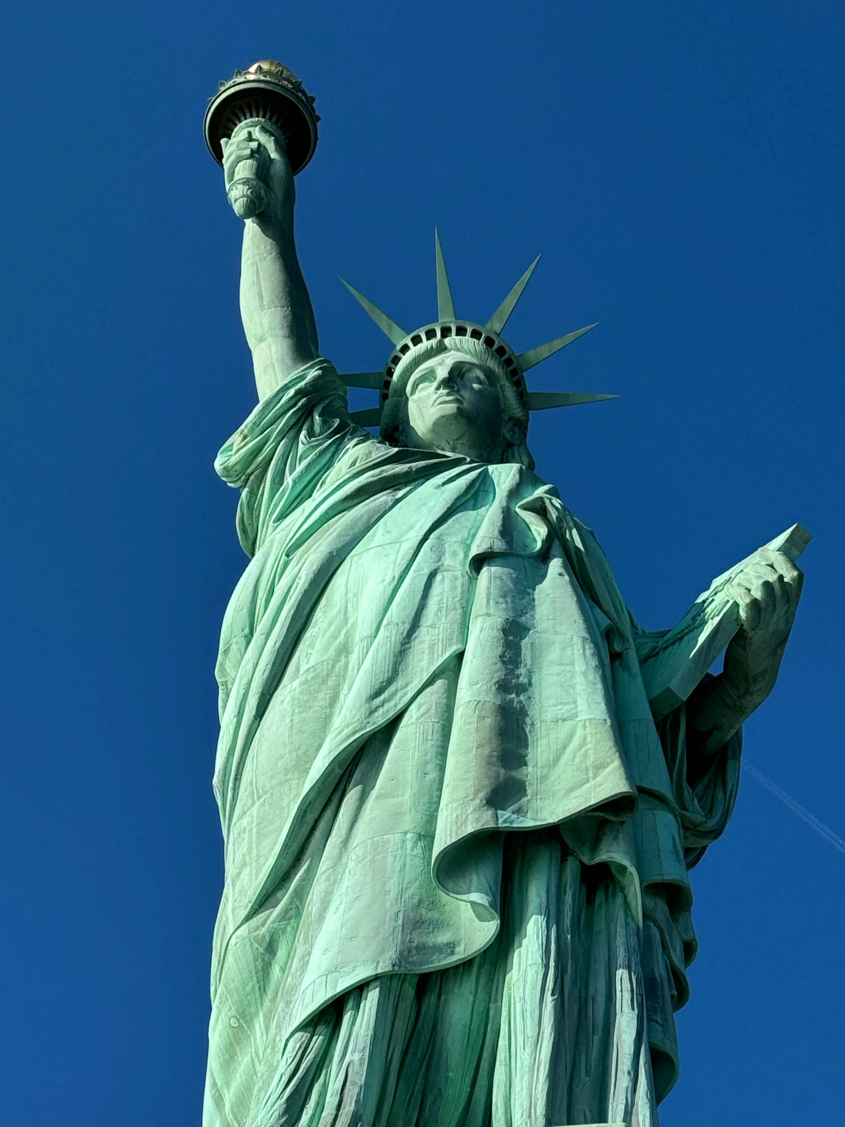 a statue of liberty on a sunny day with a bird flying by