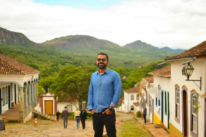 the man in blue shirt is standing in front of a mountain