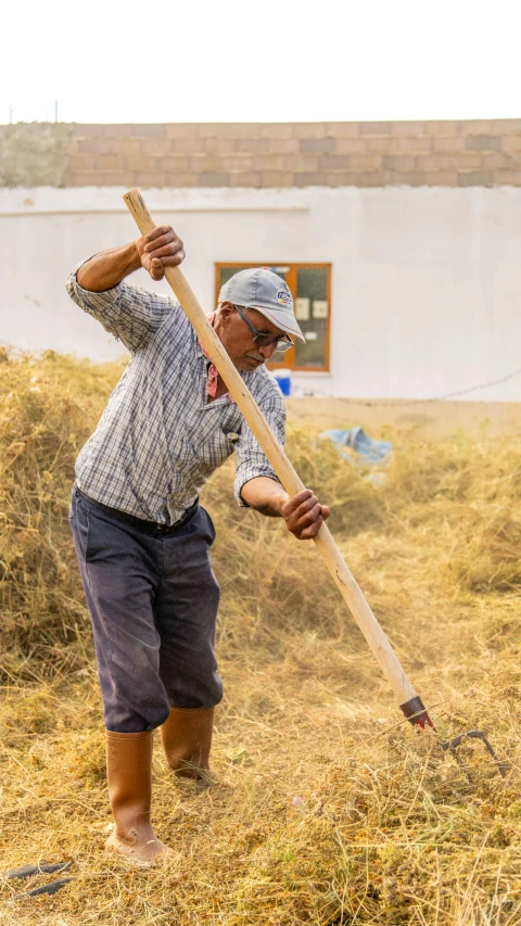 a man standing in the dry grass with a stick