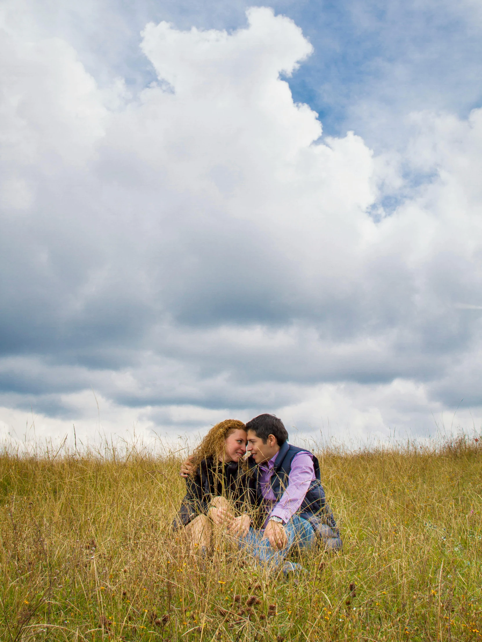 two people kissing on the grass in a field