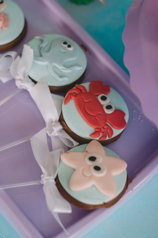 four decorated cookies in plastic boxes on a table