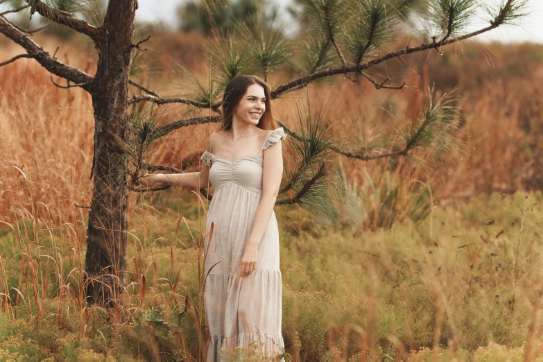 woman standing in grassy field with tree near by