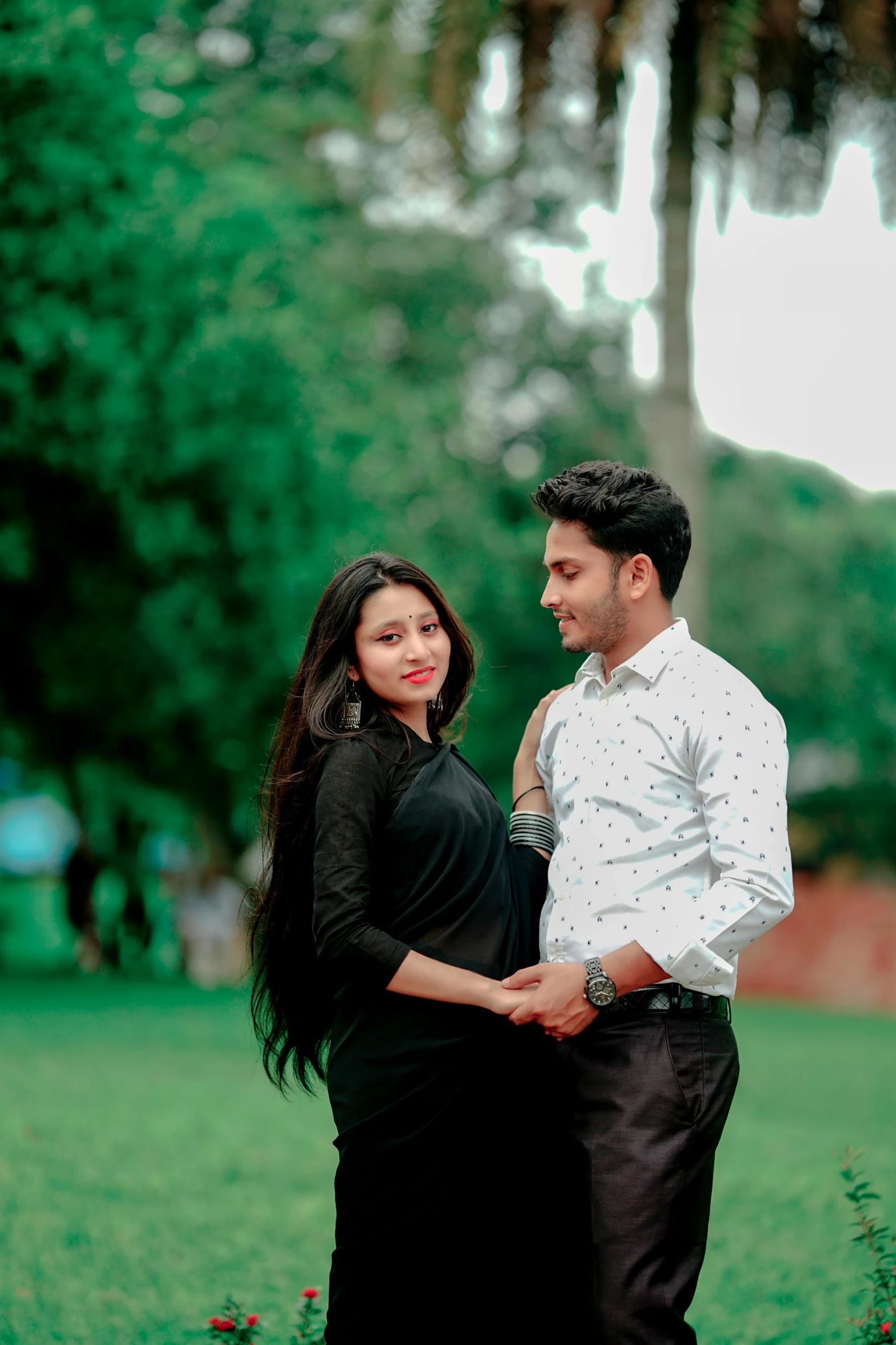 a couple posing for an image while standing together in a green field